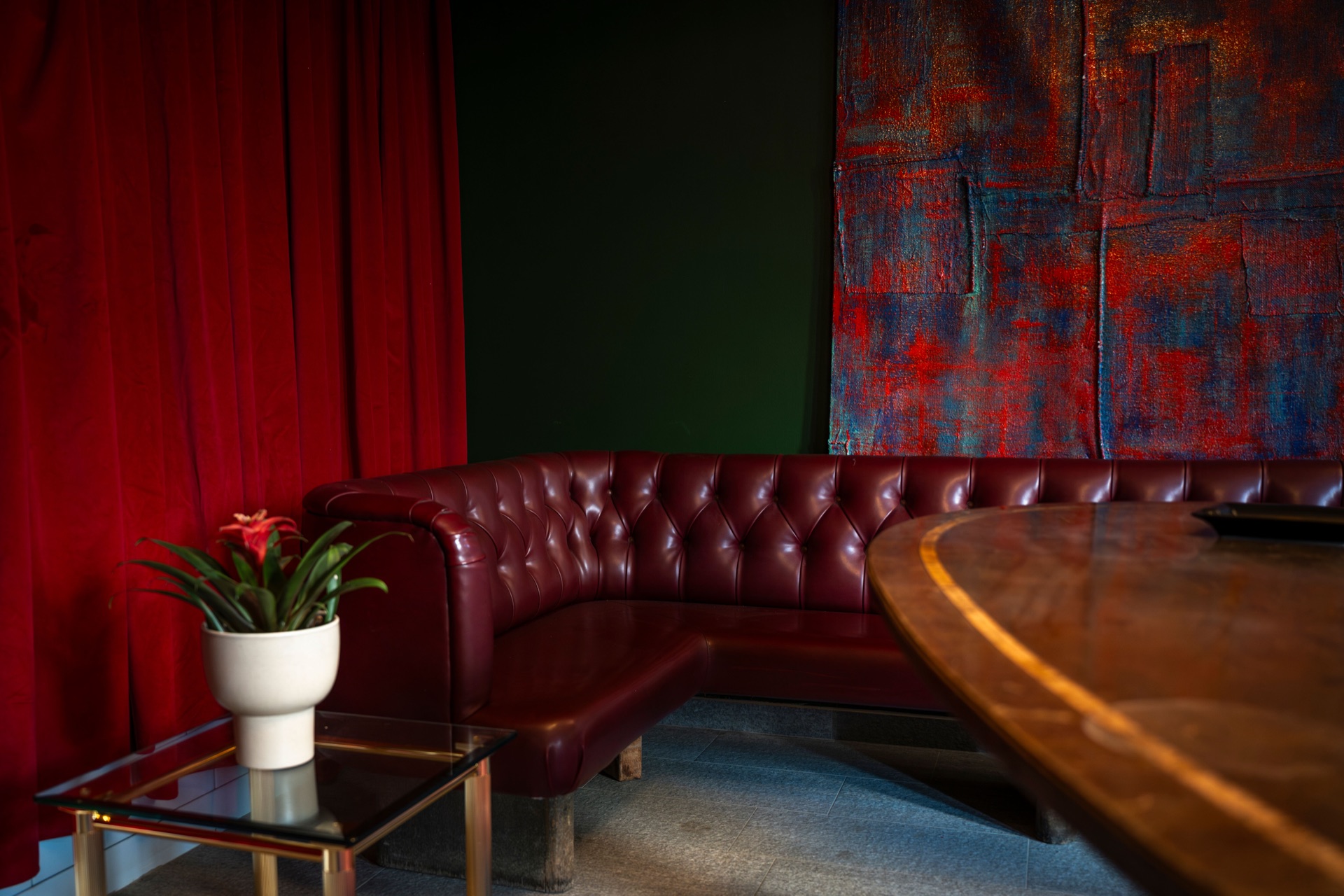 A red velvet curtain, banquette corner and textile painting at Le Bar
