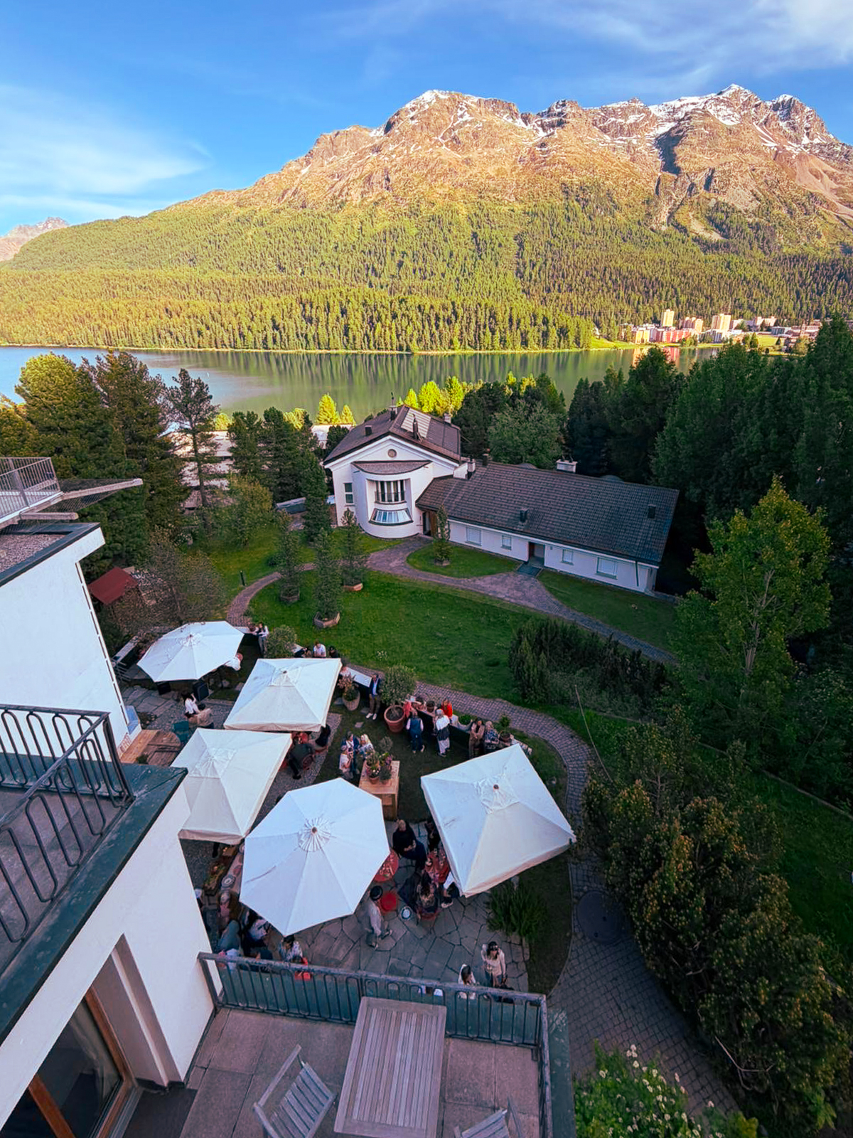 The villa garden above Lake St. Moritz, umbrellas set for the evening